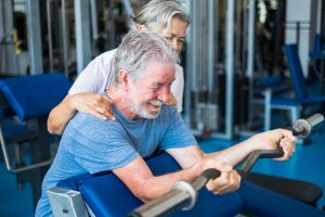 couple of seniors at the gym doing exercise together - mature woman looking