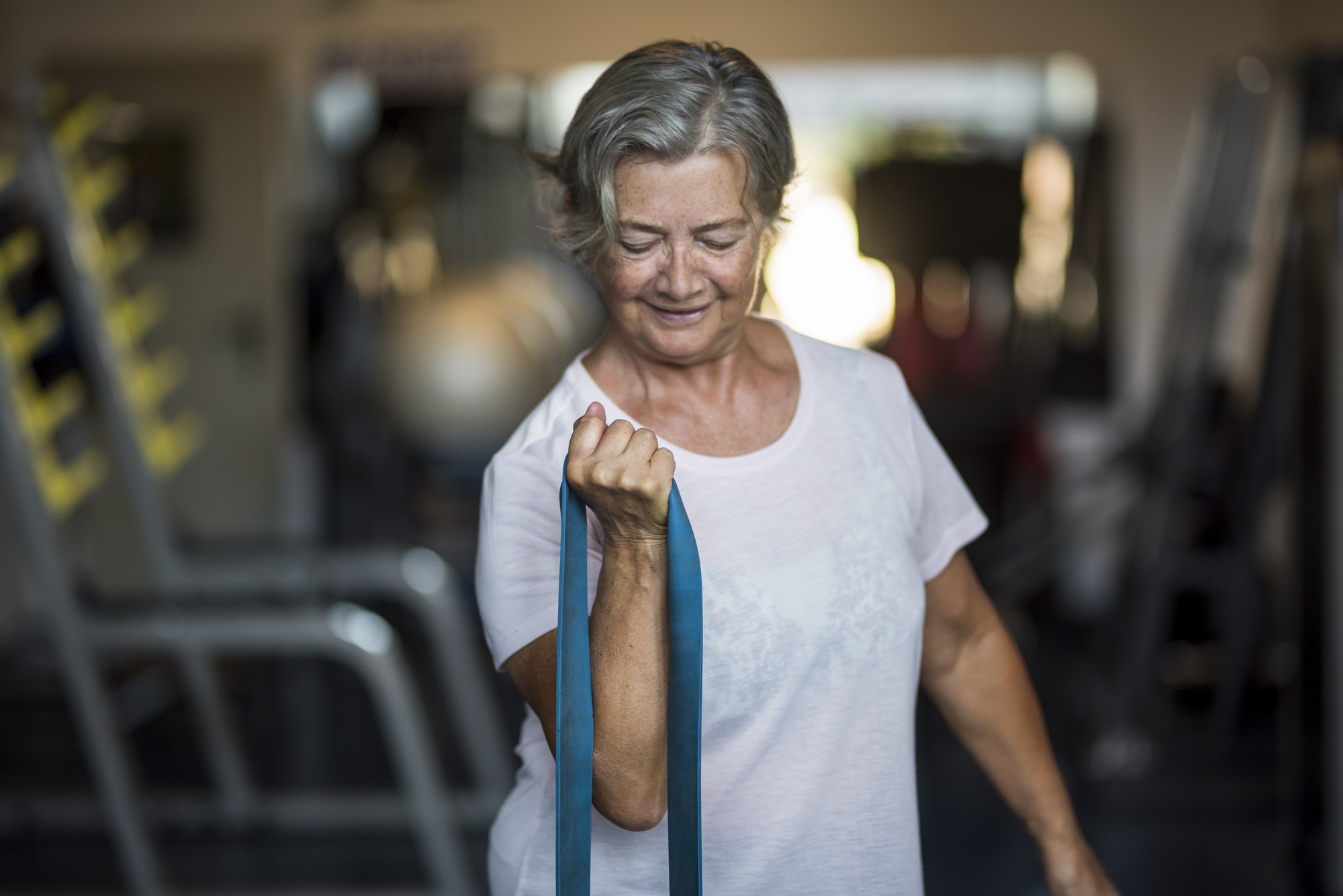 mature woman alone at the gym doing exercises with an elastic