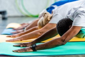 selective focus of african american sportsman with smartwatch exercising near friends at gym
